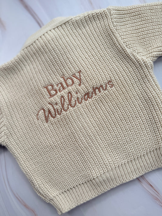 Beige baby sweater with 'Baby Williams' embroidery on a light background