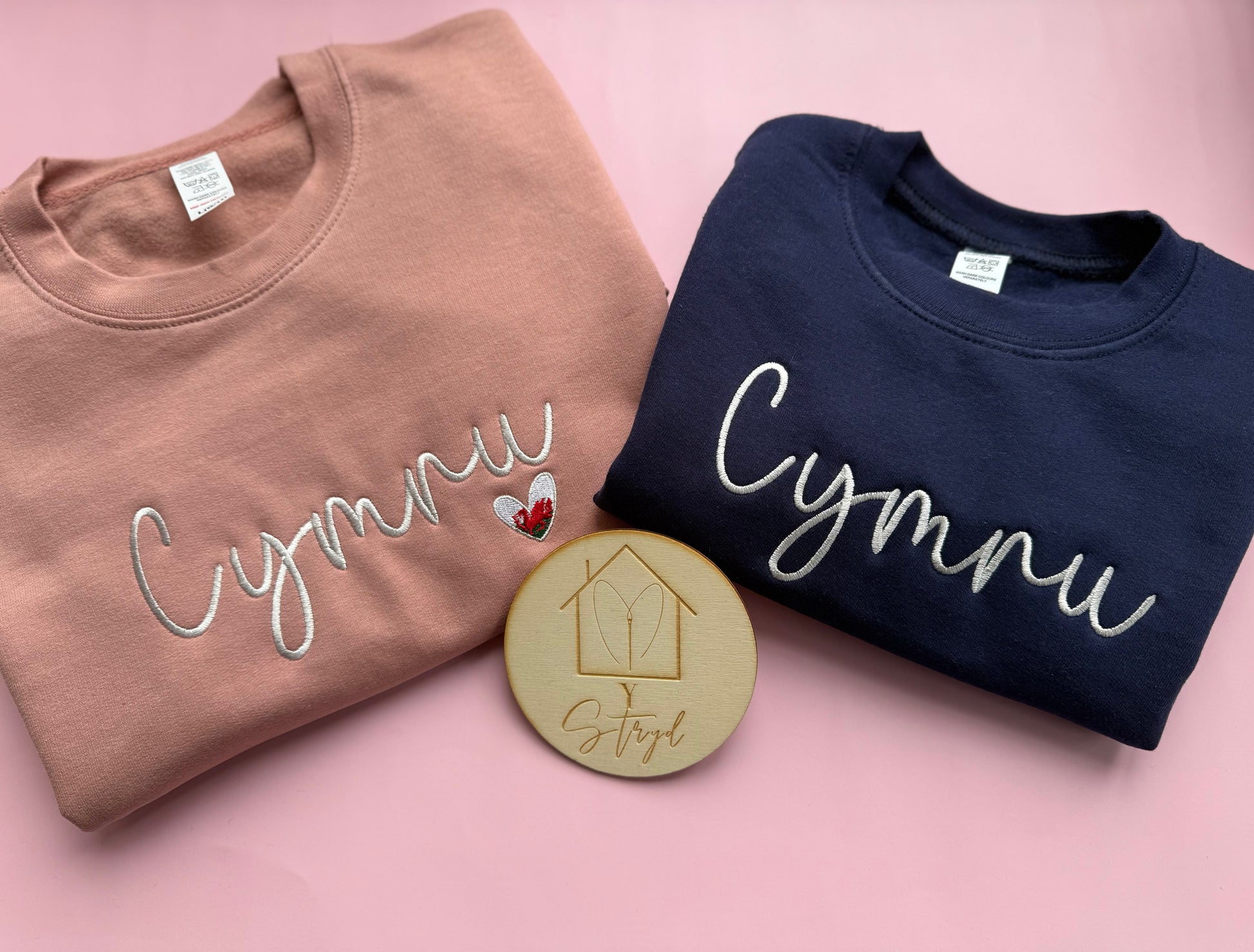 Embroidered jumpers featuring the word cymru embroidered across with a dainty Welsh flag heart